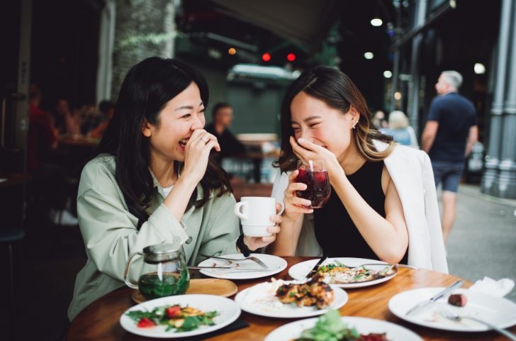 Friends laughing and enjoying dinner at The Waterview Apartments in Richmond, Texas